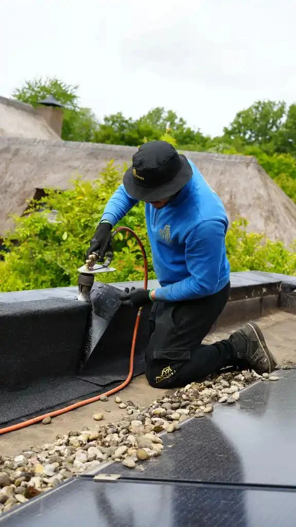 Dakdekker brandt bitumen op een dakopstand naast zonnepanelen in Barneveld