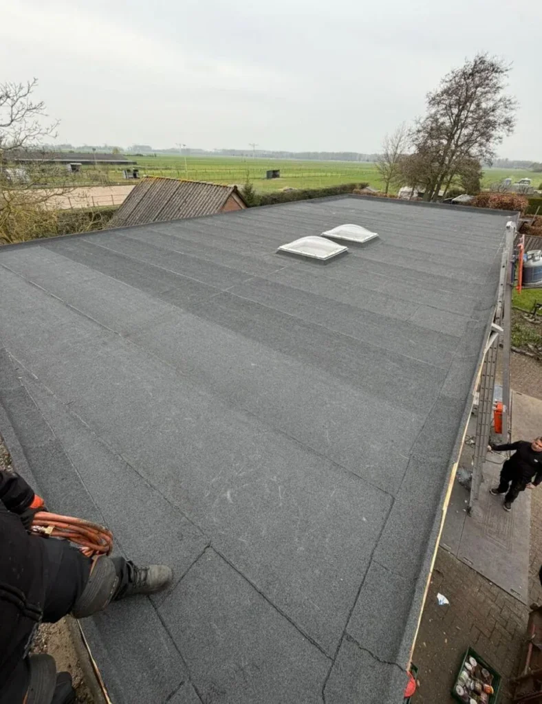 Afgewerkt plat dak met bitumen en twee lichtkoepels in Wekerom