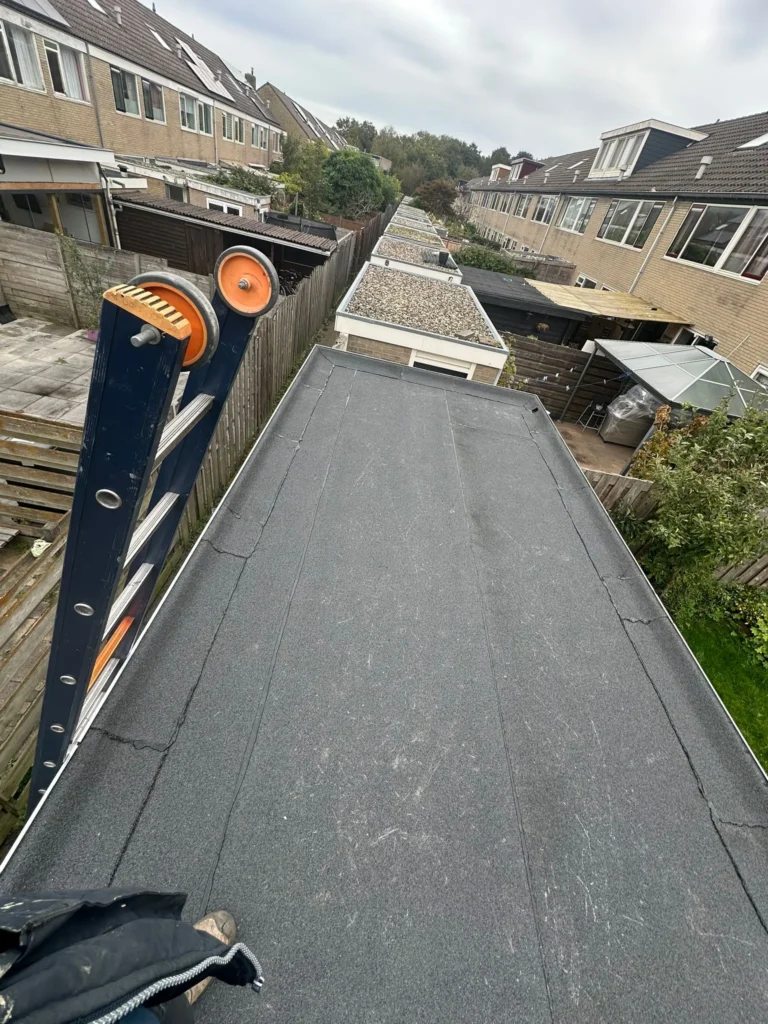 Afgewerkt plat dak met bitumen dakbedekking op een aanbouw achter rijtjeshuizen in Barneveld