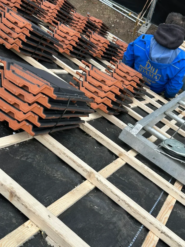 Rode dakpannen gestapeld op nieuwe panlatten, klaar om te leggen in Barneveld
