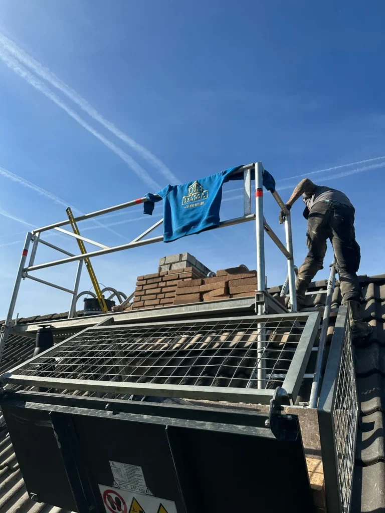 Dakdekker op een pannendak naast het platform van een ladderlift in Barneveld