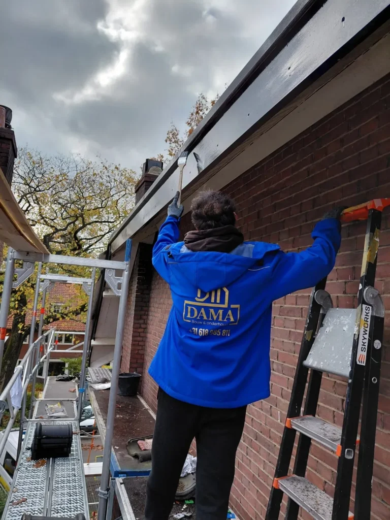 Dakdekker op een trap werkt aan de dakrand van een bakstenen woning in Barneveld