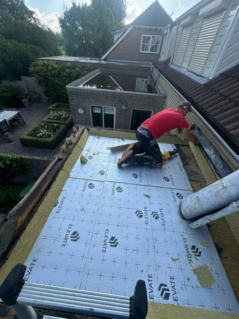 Dakdekker legt isolatieplaten op een plat dak van een aanbouw in Barneveld