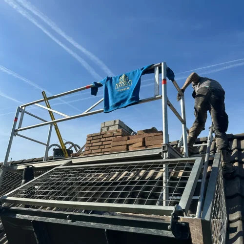 Dakdekker op een pannendak naast het platform van een ladderlift in Beekbergen