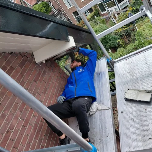 Dakdekker op een steiger werkt aan de onderzijde van een dakrand in Kootwijkerbroek